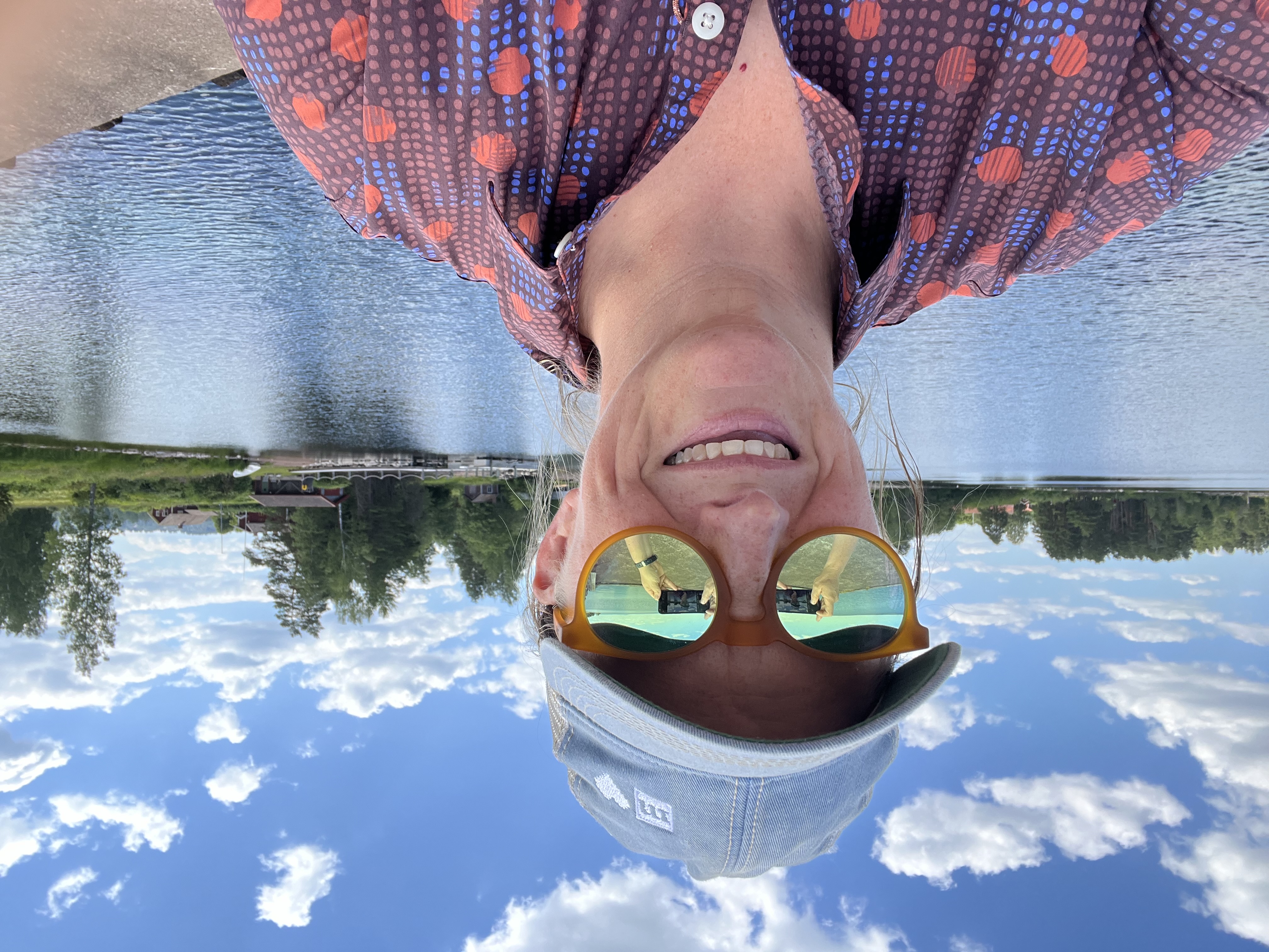 Photo of Rosanne in sunglasses in front of water, uploaded upside down for unknown reason! 